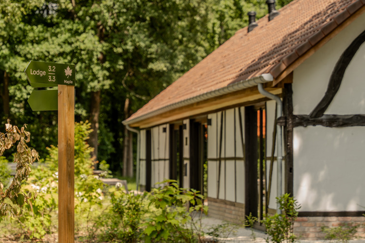 Schild und Fachwerk-Lodge, Villa Lodge mit Jacuzzi bei Woodz Lodges in Belgien, im Grünen gelegen.
