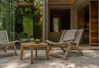 Terrace at the Wellness Suite, Woodz Lodges in Belgium, featuring modern lounge chairs and a wooden table.