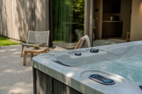 Outdoor hot tub at the Wellness Suite, Woodz Lodges in Belgium, next to a patio and cozy seating area.