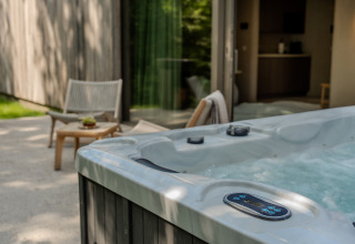 Outdoor hot tub at the Wellness Suite, Woodz Lodges in Belgium, next to a patio and cozy seating area.