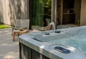 Buitenjacuzzi bij de Wellness Suite van Woodz Lodges in België met terras en zitgedeelte naast het huis.
