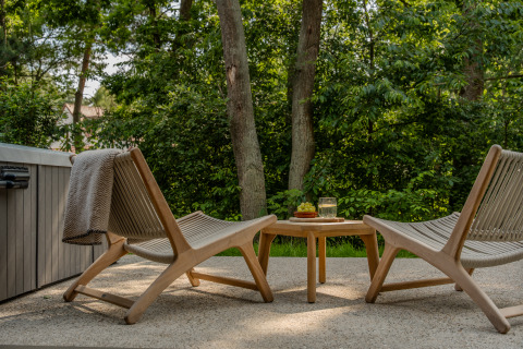 Two outdoor chairs and a small table with snacks and a drink on a patio at Wellness Suite, Woodz Lodges, Belgium.