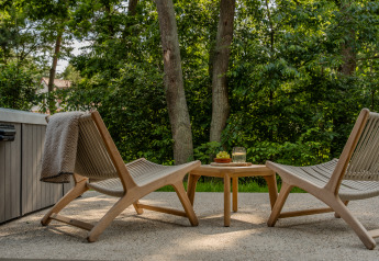 Twee buitenstoelen en een tafeltje met snacks en een drankje op het terras bij Wellness Suite, Woodz Lodges.
