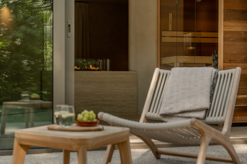 Relaxing lounge area at the Wellness Suite in Woodz Lodges, Belgium, featuring chair, table, and sauna.