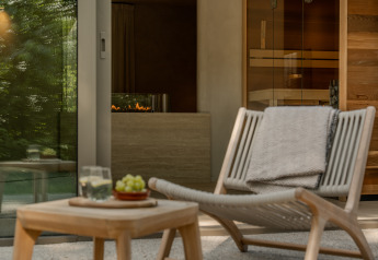Ontspannende loungehoek in de Wellness Suite bij Woodz Lodges, België, met stoel, tafel en sauna.