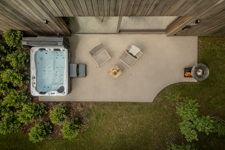 Vista aérea de la Wellness Suite en Woodz Lodges, Bélgica, con jacuzzi, tumbonas y pozo de fuego exterior.