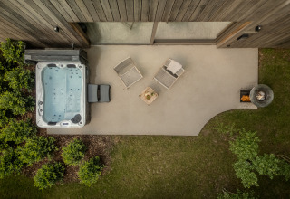 Vista aérea de la Wellness Suite en Woodz Lodges, Bélgica, con jacuzzi, tumbonas y pozo de fuego exterior.