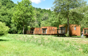 Houten chalets aan Cocoon de l’Ourthe in Hameau de l'Ourthe, België, omringd door groene natuur.