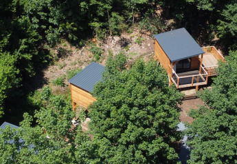 Vista aérea de casas en los árboles rodeadas de vegetación en Tree House, Hameau de l'Ourthe, Bélgica.