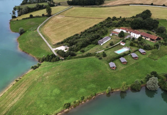 Vista aerea di un glamping con tende safari, piscina e lago al Domaine La Barbe, Francia, immerso nella natura.