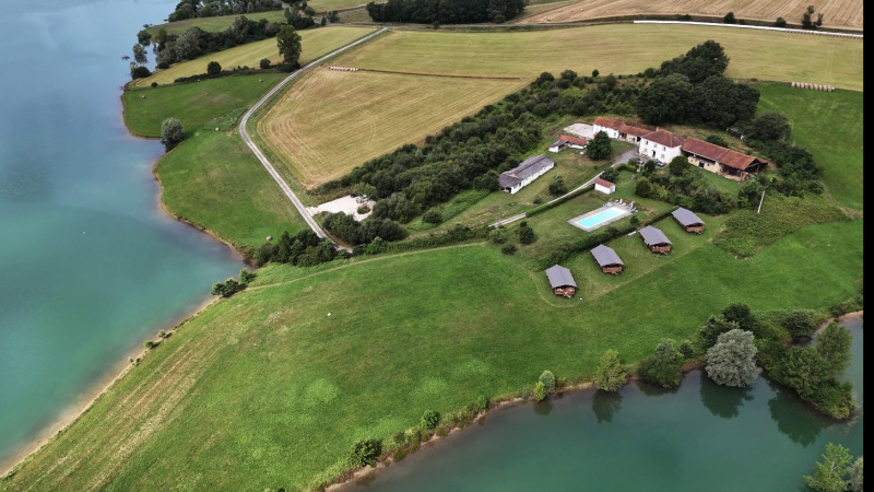 Vista aerea di un glamping con tende safari, piscina e lago al Domaine La Barbe, Francia, immerso nella natura.