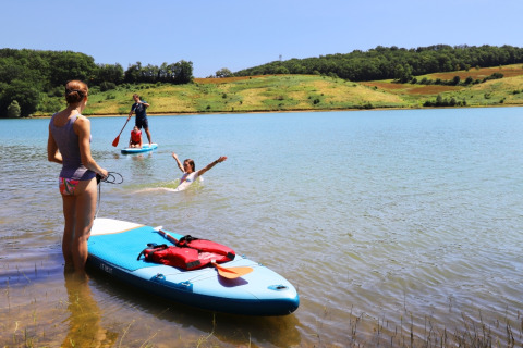 Des personnes font du paddle et nagent sur le lac du Domaine La Barbe, un parc de vacances en Occitanie, France.