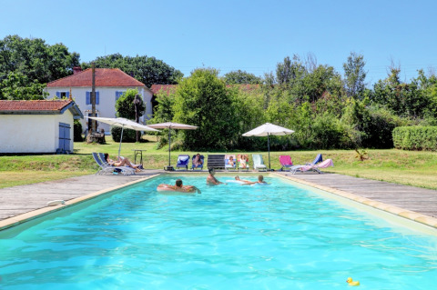 Piscine extérieure avec vacanciers, transats et parasols au Domaine La Barbe, village vacances en Occitanie, France.