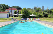 Outdoor swimming pool with guests, sun loungers, and umbrellas at Domaine La Barbe holiday park in Occitanie, France.