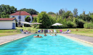 Piscine extérieure avec vacanciers, transats et parasols au Domaine La Barbe, village vacances en Occitanie, France.