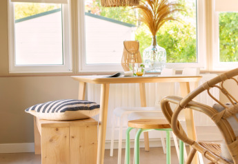 Rincón comedor iluminado en tiny house de Zomerhuisjes, Beloofde Land, Países Bajos, con muebles de madera.