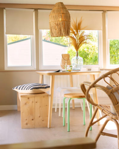 Rincón comedor iluminado en tiny house de Zomerhuisjes, Beloofde Land, Países Bajos, con muebles de madera.