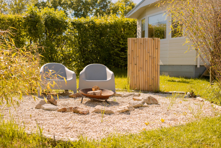 Deux fauteuils modernes et un foyer sur gravier près d’une tiny house à Beloofde Land, Pays-Bas.