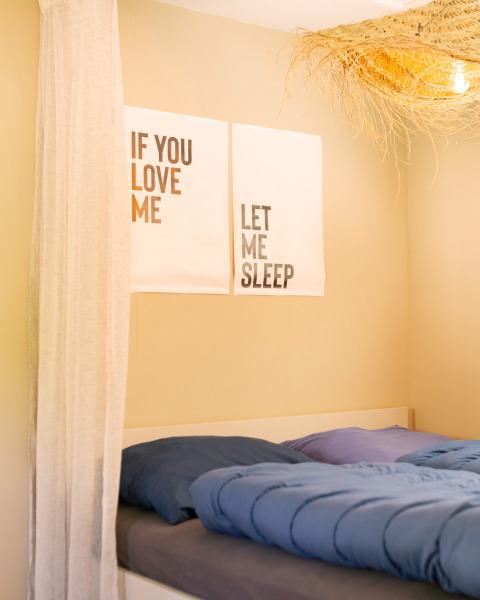 Bright bedroom in a tiny house at Zomerhuisjes, Beloofde Land in the Netherlands, with playful wall posters.