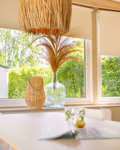 Interieur van een zomerhuisje in Nederland met glazen vaas, droogbloemen en veel natuurlijk licht.