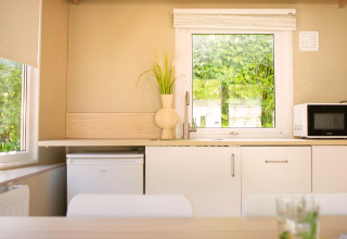 Modernes, helles Minihaus-Kücheninterieur bei Zomerhuisjes, Beloofde Land, Niederlande, mit Fensterblick.
