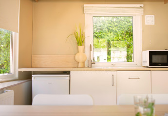 Cuisine moderne et lumineuse dans une tiny house à Zomerhuisjes, Beloofde Land, Pays-Bas, avec fenêtre et micro-ondes.