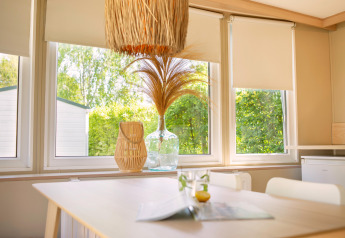 Interno soleggiato di una tiny house Zomerhuisjes a Beloofde Land, Paesi Bassi, con vista verde dalle finestre.