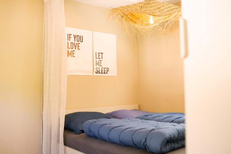 Pequeño dormitorio en Zomerhuisjes en Beloofde Land, Países Bajos, con manta azul y arte en la pared.