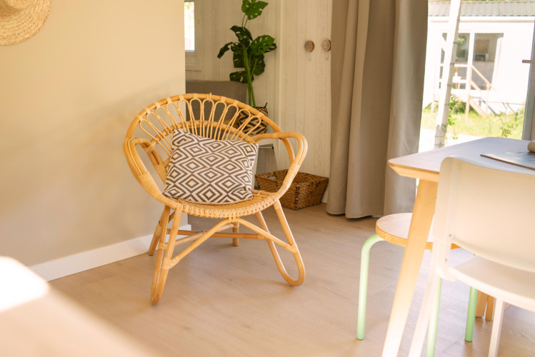 Intérieur lumineux d'une tiny house aux Zomerhuisjes, Beloofde Land, Pays-Bas, avec fauteuil en rotin.