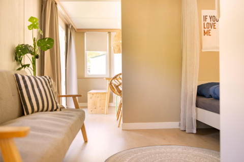 Helles, gemütliches Interieur eines Zomerhuisjes im Beloofde Land, Niederlande, mit Sofa und Bett.