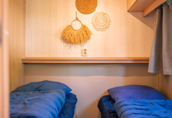Two single beds with blue bedding in a tiny house at Zomerhuisjes, Beloofde Land, Netherlands.