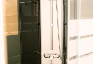Modern shower setup in a tiny house at Zomerhuisjes, Beloofde Land, Netherlands, with glass door.