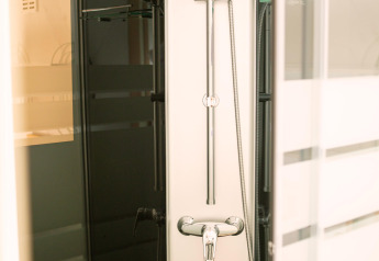 Modern shower setup in a tiny house at Zomerhuisjes, Beloofde Land, Netherlands, with glass door.