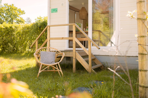 Kleines Ferienhaus Zomerhuisjes am Beloofde Land in den Niederlanden, mit Stuhl und Kissen im Garten.