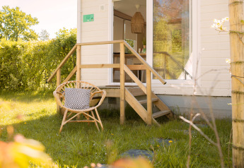 Petite maison Zomerhuisjes à Beloofde Land aux Pays-Bas, avec chaise et coussin sur la pelouse.