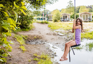 Une fille sur une balançoire devant une tente safari Boerderij à Beloofde Land, Pays-Bas, entourée de nature.