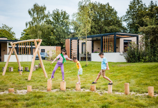 Des enfants jouent dehors sur des rondins devant une tente safari à Boerderij huisje, Beloofde Land, Pays-Bas.