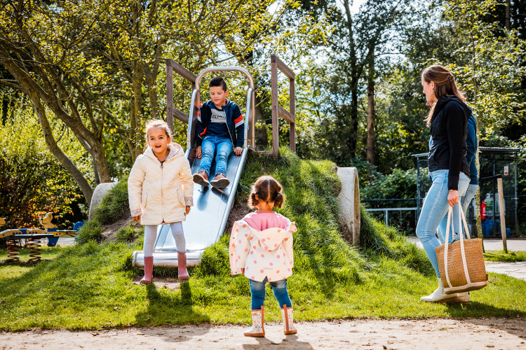 Children playing on a slide at Boerderij huisje, Beloofde Land in the Netherlands, watched by an adult.