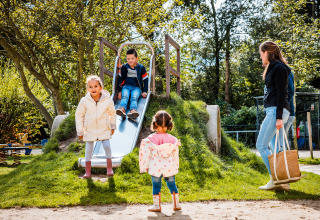 Des enfants jouent sur un toboggan au Boerderij huisje, Beloofde Land aux Pays-Bas, sous la surveillance d'une adulte.