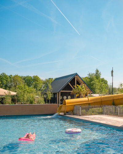 Piscine extérieure avec toboggan jaune et bouée près de Jippi Tippi au Beloofde Land, Pays-Bas, journée ensoleillée.