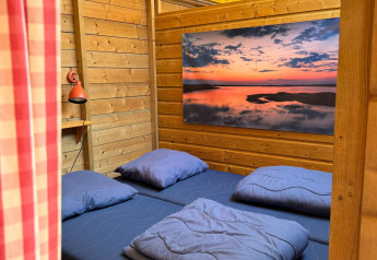 Interno di una cabina in legno con letto matrimoniale e biancheria blu a Zweedse Huisjes, Beloofde Land.