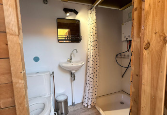 Salle de bain moderne avec WC, lavabo, douche, miroir et murs en bois au Zweedse Huisjes, Beloofde Land.