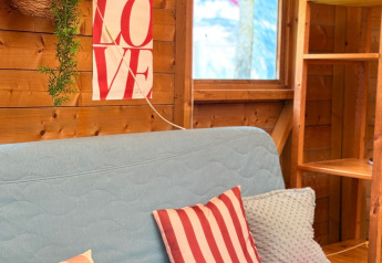Intérieur douillet d’un lodge aux Zweedse Huisjes, canapé bleu, coussins rayés et affiche LOVE sur le mur.
