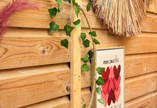 Decorative wooden fence with leafy garland, handmade wall decor, and French heart sign in a cozy lodge.