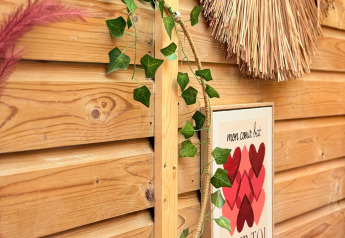Cerca de madera decorativa con guirnalda, decoraciones y cartel francés de corazones en una cabaña acogedora.