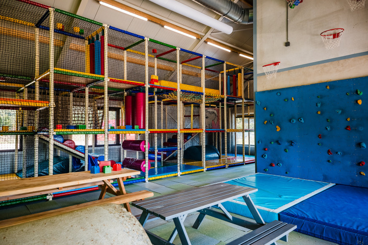 Indoor-Spielplatz mit Kletterwand, Schaukeln und Ballspiel in einem Safarizelt in Beloofde Land, Niederlande.