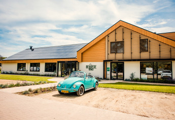 Blauwe oldtimer geparkeerd bij Safaritent basic op Beloofde Land, Nederland, bij zonnig en helder weer.