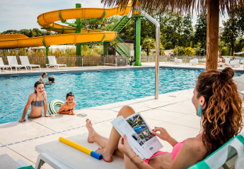 Een moeder rust uit bij het zwembad terwijl kinderen spelen in het water aan Safaritent basic, Beloofde Land.
