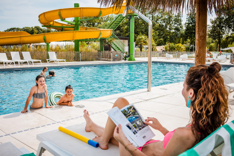 A mother relaxes by the pool while children play in the water at Safaritent basic, Beloofde Land, Netherlands.