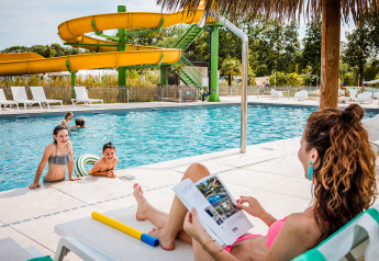 Een moeder rust uit bij het zwembad terwijl kinderen spelen in het water aan Safaritent basic, Beloofde Land.